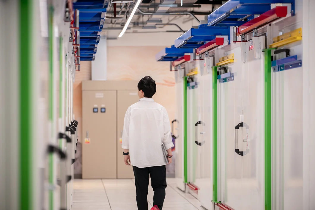 A person wearing a white shirt and black pants standing in a lab facility with glass doors