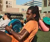 Man wearing an orange shirt does Russian Twist ab exercises while holding a weight and wearing a Charge 6.