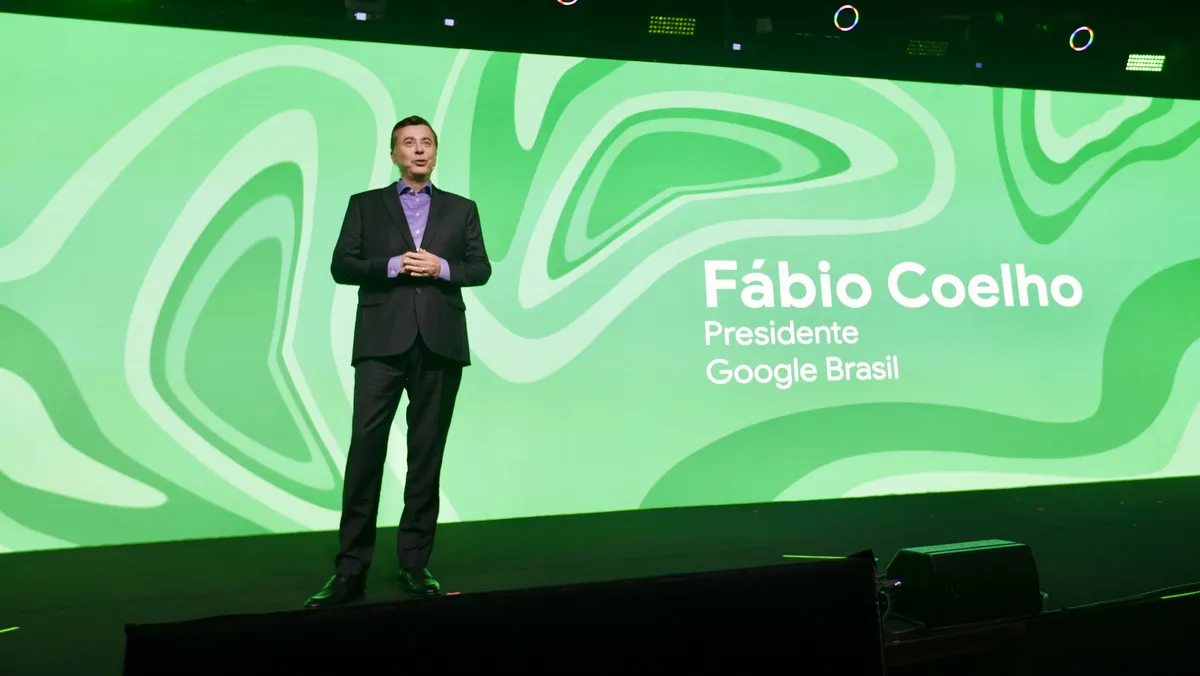 Fabio Coelho, country director for Brazil, stands on the stage with a big green screen behind him that says his name