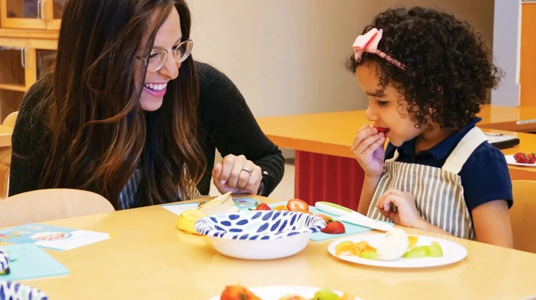 Woman helping feed a young child