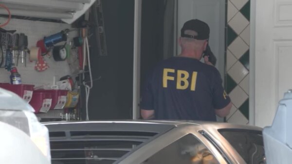 man in hat and FBI tshirt stands with back to camera