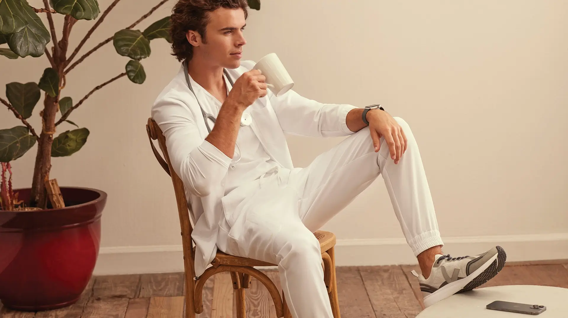 man wearing medical scrubs and drinking coffee