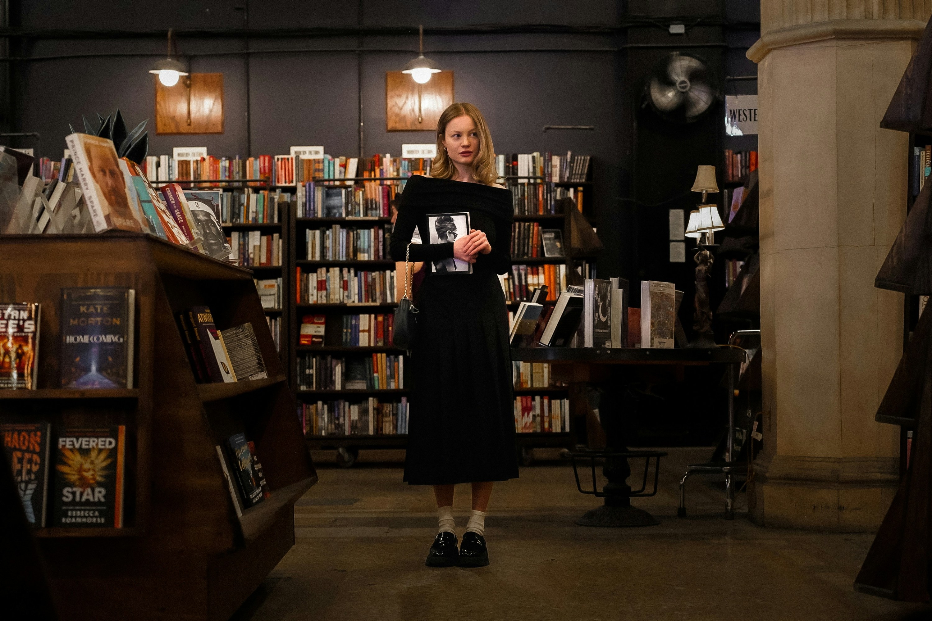 A young woman stands in a book store.