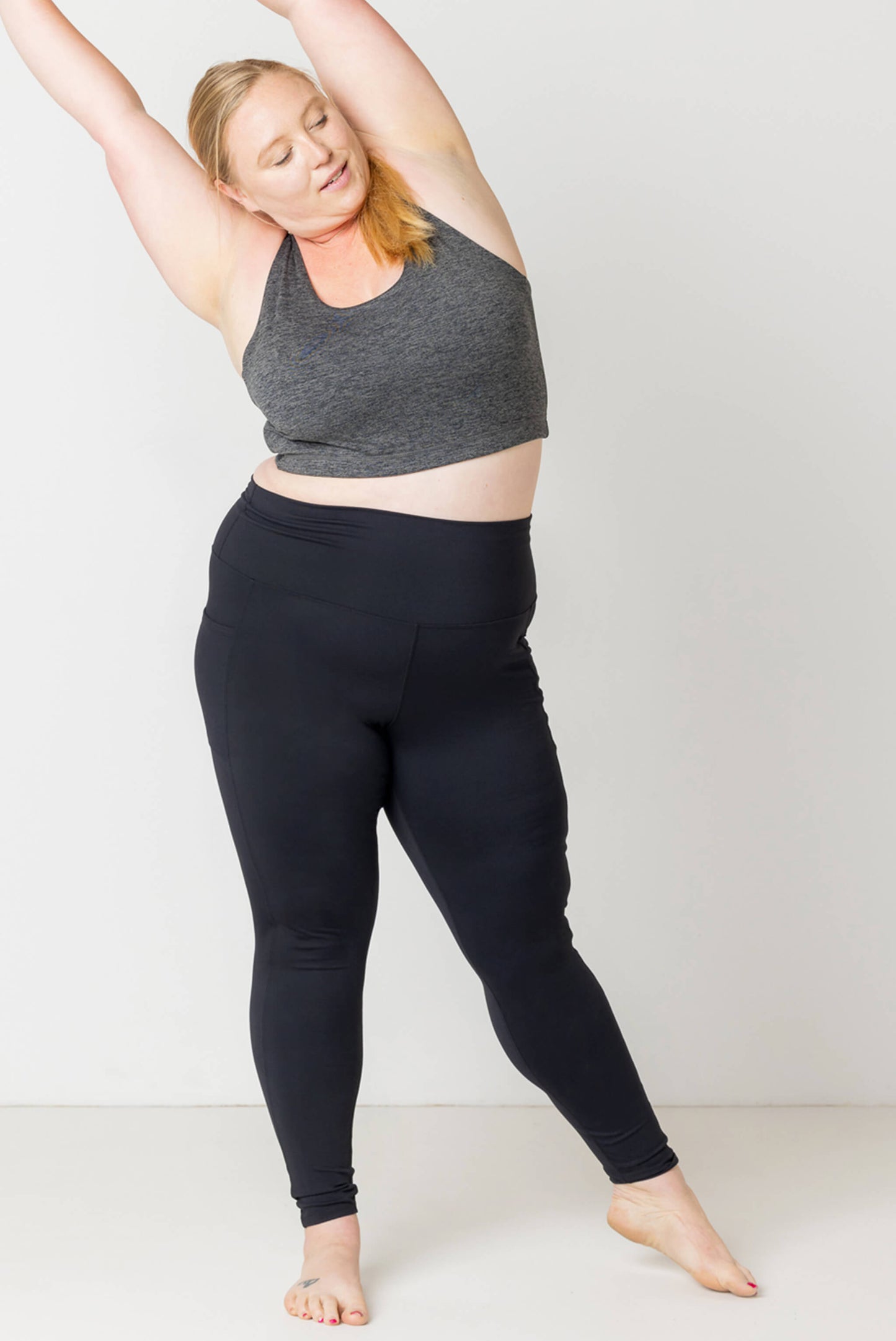 Model is stretching in her black Superfit Hero SuperHold pocket leggings size 2X