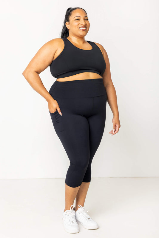 Full body view of plus size model wearing black SuperHold pocket capris in size 2x