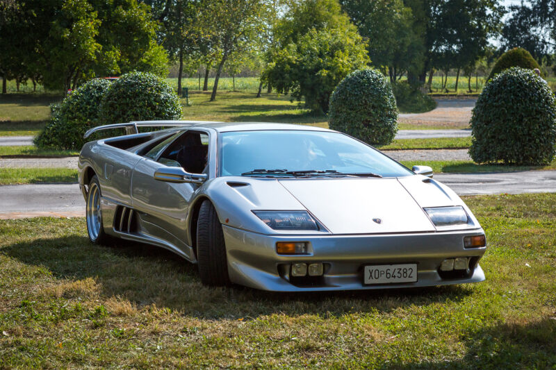 Grey Lamborghini Diablo parked in on the grass in a park.