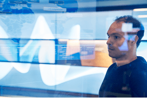 A photo of a man in a security center monitoring for cyberattacks.