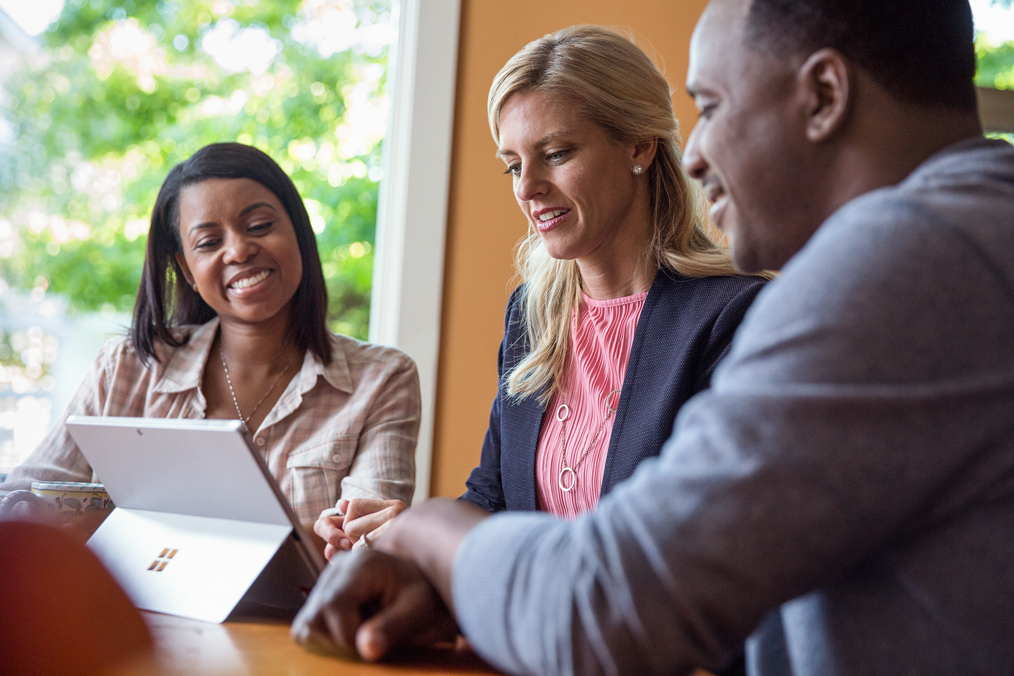 Photo of a three people looking at a Microsoft Surface together