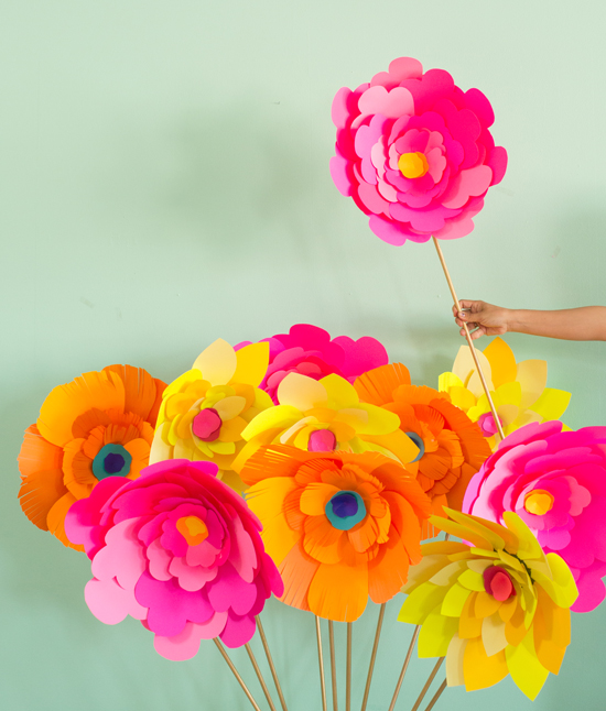 Large paper flowers in vibrant colors on wooden stems to create a bouquet.