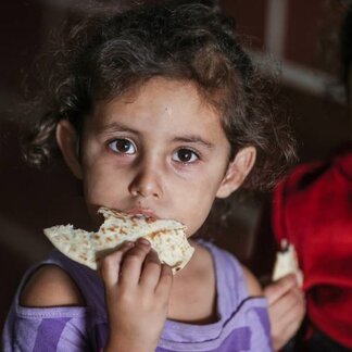 En flicka äter bröd. Foto: WFP/Ali Jadallah