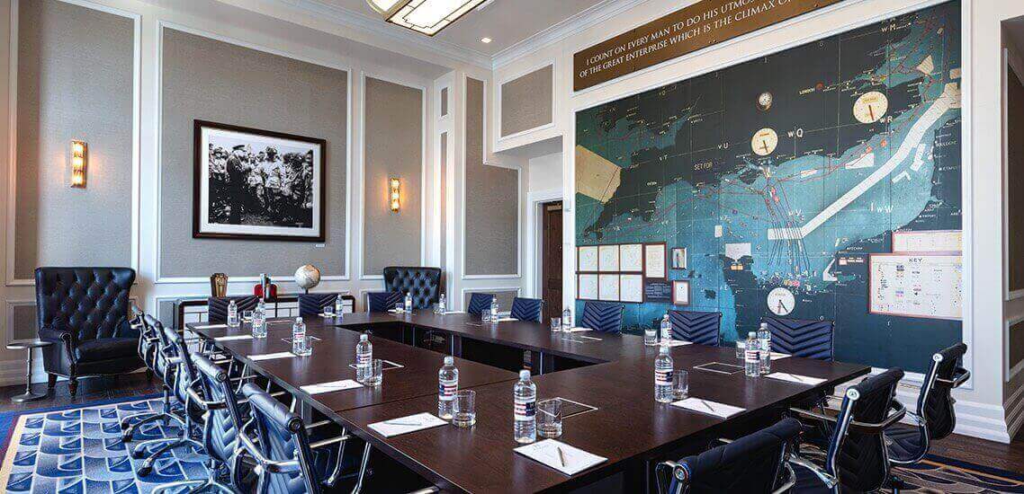 Long table with cushioned chairs set up for meeting