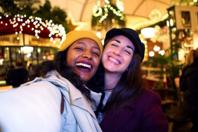 Two friends taking a selfie smiling side by side.