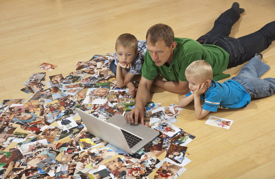 Family watching laptop on the floor, photos around