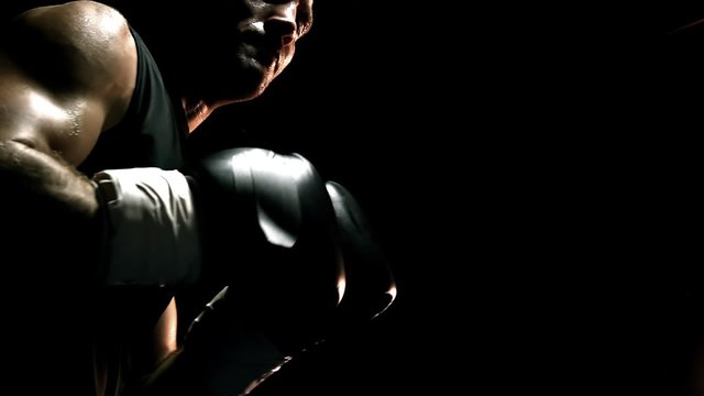 Muscular athlete practices boxing on a punching bag. Close up shot.