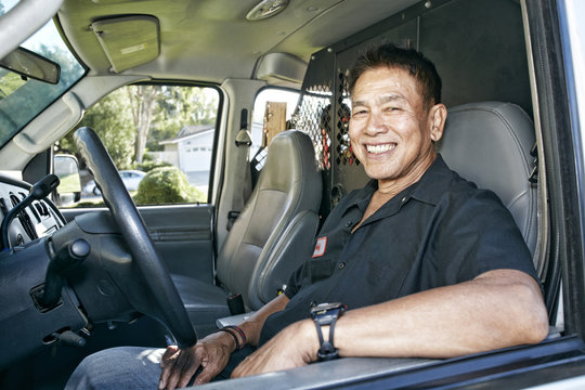 Pacific Islander plumber smiling in van