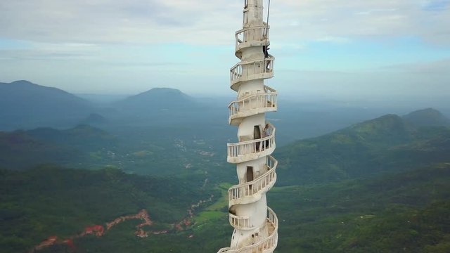 Round view girl climbs the stairs on white tower top hill sunrise drone footage