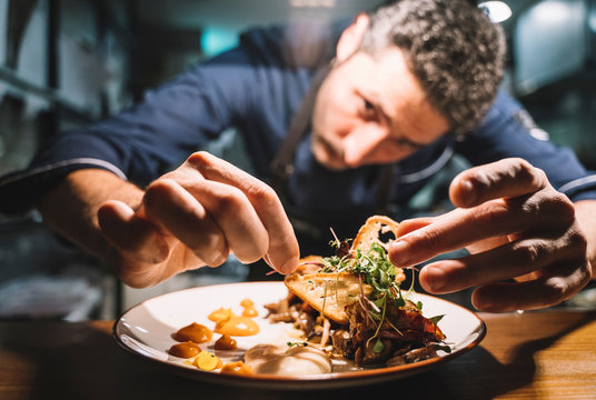 Professional cook arranging food on plate