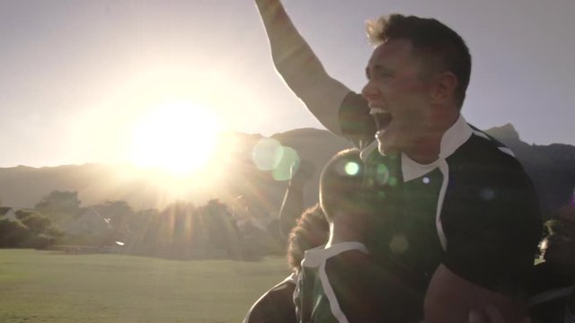 Excited rugby players celebrating win at the field. Rugby team enjoying after the victory.