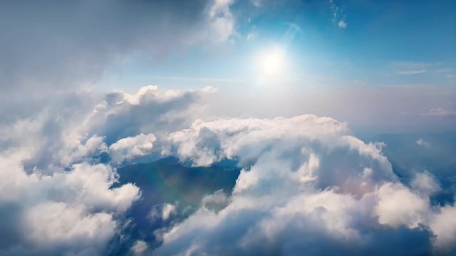 Flying through heavenly beautiful sunny cloudscape. Amazing timelapse of white fluffy clouds moving softly on the sky and the sun shining above the clouds with beautiful rays and lens flare. 