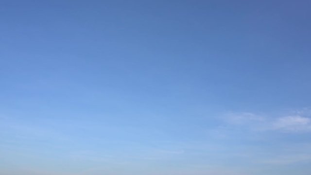 Time lapse of peaceful sunny blue sky with soft white clouds running along. Plane flying at end of clip.