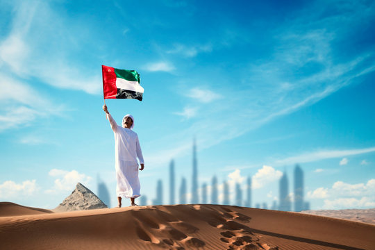 Arab man holding the UAE flag in the desert celebrating UAE national day and Uae flag day.