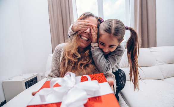 Happy mother's day.  Child daughter surprise mom giving her a gift. Concept about family and love