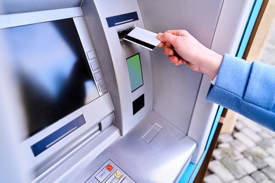 Person insert plastic credit card into street atm bank to withdrawing money