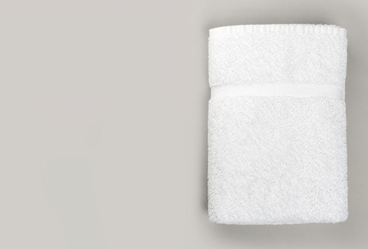 Top view of folded clean white bathroom towel on gray background with copy space