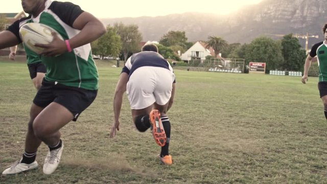 Rugby players tackling for ball possession during the game. Professional players playing rugby on field.
