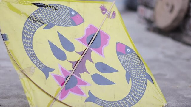 Footage of kite festival in India where a young boy is trying to fly a yellow kite on his roof with selective focus.