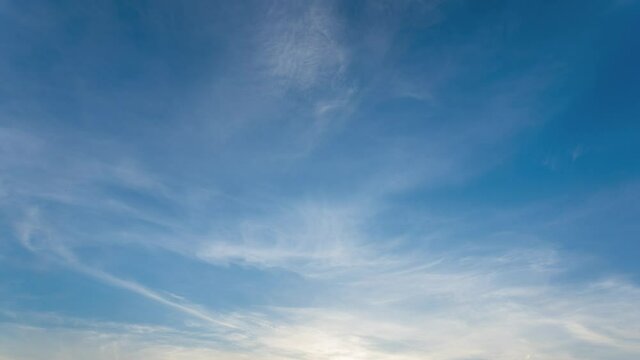 Blue sky video background. Time lapse of beautiful sunset peaceful clear sunny spring sunset sky with soft delicate white clouds moving along