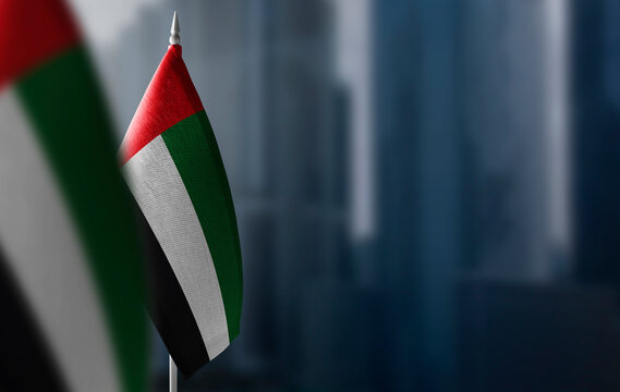 Small flags of United Arab Emirates on a blurry background of the city