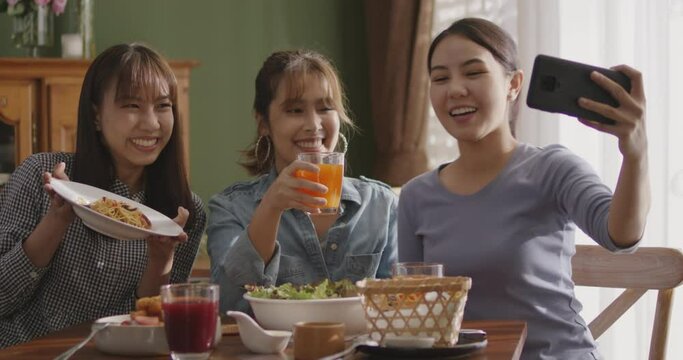 Small girl group party asia people busy talk smile eat brunch food drink. Young woman fun happy hour meal shoot photo of dish plate salad bowl on table post ig reel story app in vegan cafe bar shop.