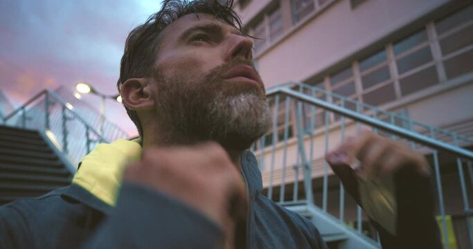 Tired and sweaty athlete man running for intense cardio training outside in urban city. Closeup sportive fitness male breathing heavily and resting while preparing for race, boxing match or marathon