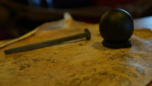 close up old naval map with cannon ball and nail