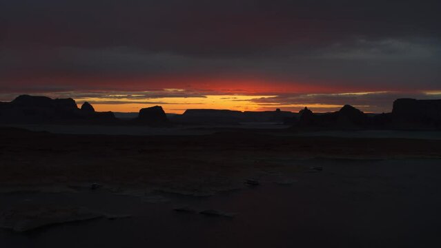 Sunset over silhouette of rock formations in desert under dramatic sky / Glen Canyon National Recreation Area, Utah, United States