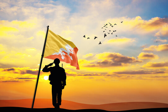 Silhouette of a soldier with the Bhutan flag stands against the background of a sunset or sunrise. Concept of national holidays. Commemoration Day.