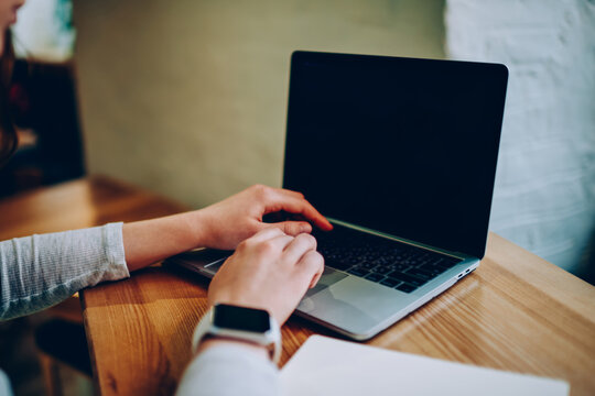 Cropped image of female freelancer using laptop computer for searching information and browsing website on blank monitor,woman using netbook application with mock up screen for e learning in cafe