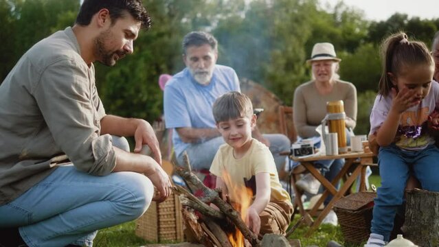 A father and little boy son happily start a campfire during a family camping trip in nature