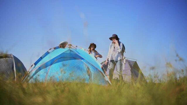 Travellers camping family under set up camp site Pulls and sticks a metal tent peg into the ground is holiday activity with mountain nature lifestyle.