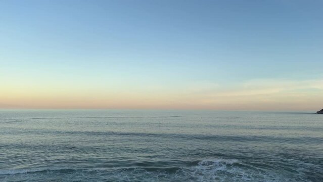 Peaceful endless ocean waves rolling in at sunset in 4k landscape footage with sunset sky horizon line