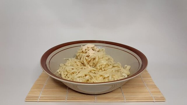 A simple bowl of Indomie instant fried noodles topped with dried vegetables and sprinkled spices on top, isolated background.