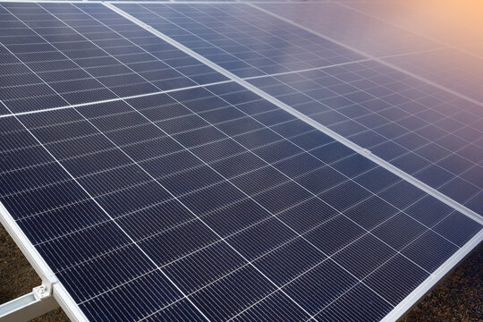 Close up of solar panel surface at solar farm on land with morning sunlight flare