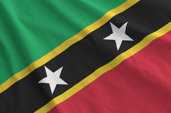 Saint Kitts and Nevis flag depicted on folded wavy fabric of old cloth close up