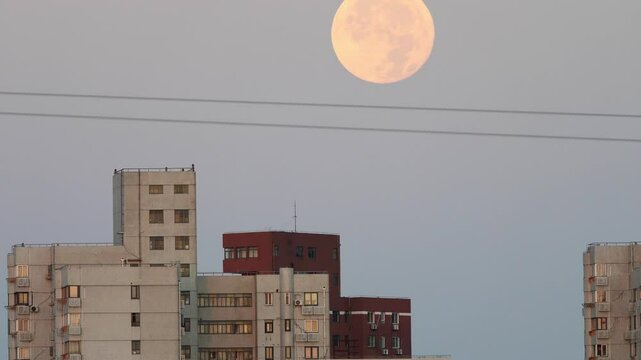 4k time lapse footage of full moon falling down behind modern residential building in Shanghai city.