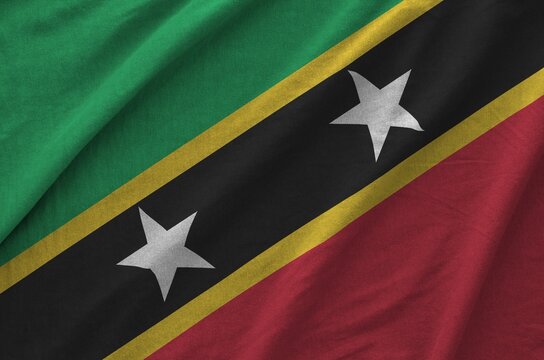 Saint Kitts and Nevis flag depicted on folded wavy fabric of old cloth close up