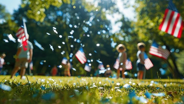 A blurred background of children playing in the park with American flags, stars and stripes flying around them and focus an American flag in front.