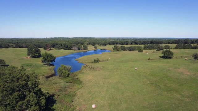 Drone footage of a pond and hay bales in a rural Oklahoma pasture