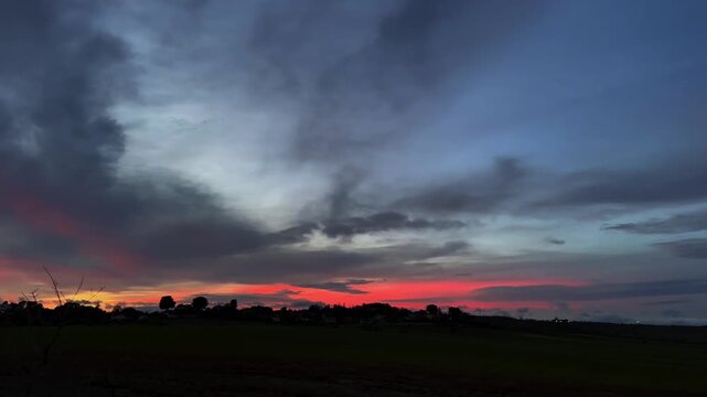 Beautiful landscape with evening dark blue red cloudy sky at sunset in a field. Slow motion footage with magical landscape in twilight. Dark skyline. 