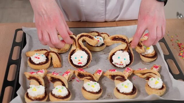 Freshly baked Easter pastries. The girl's hands demonstrate Easter bunnies, rabbits to the camera
close-up. Homemade aromatic pastries, Easter food, Easter holiday, front view.